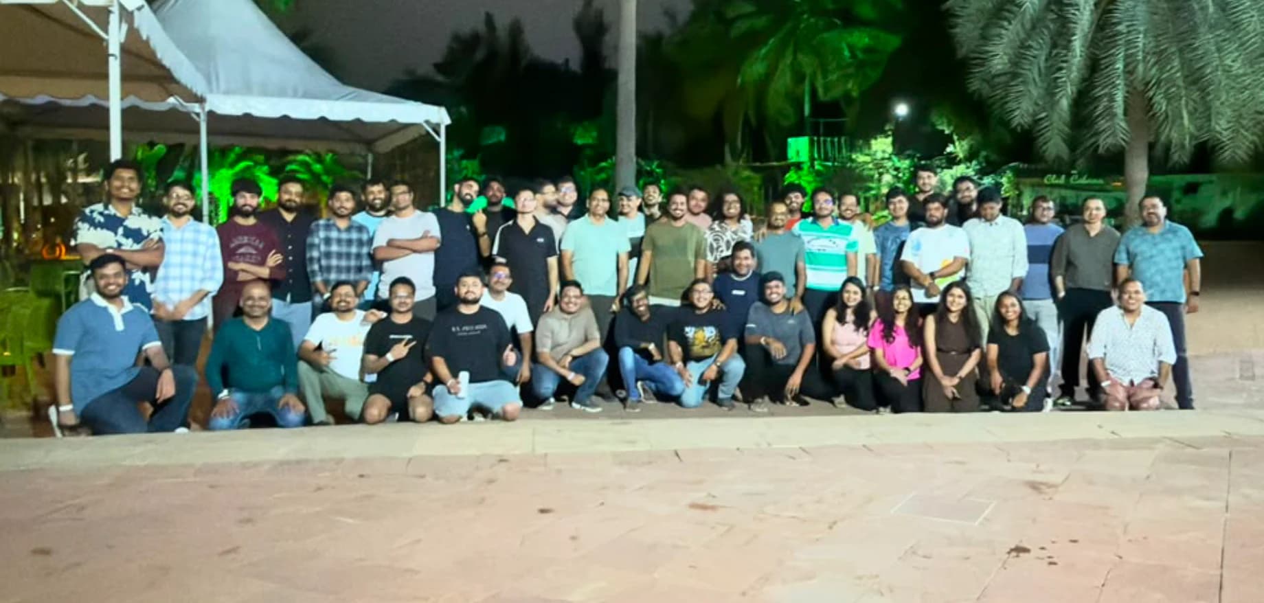 A large group of colleagues posing together outdoors at night.